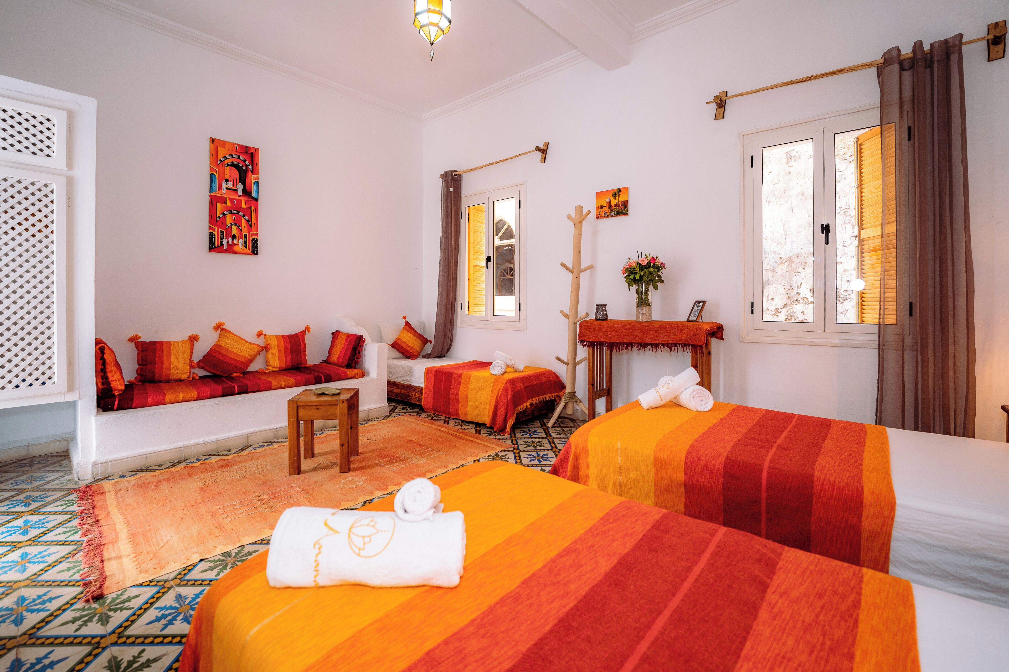 A hotel room with two beds, a sofa, a small table, and a window with curtains.