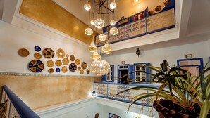 Un interior de varios niveles con una escalera, platos decorativos e iluminación colgante.