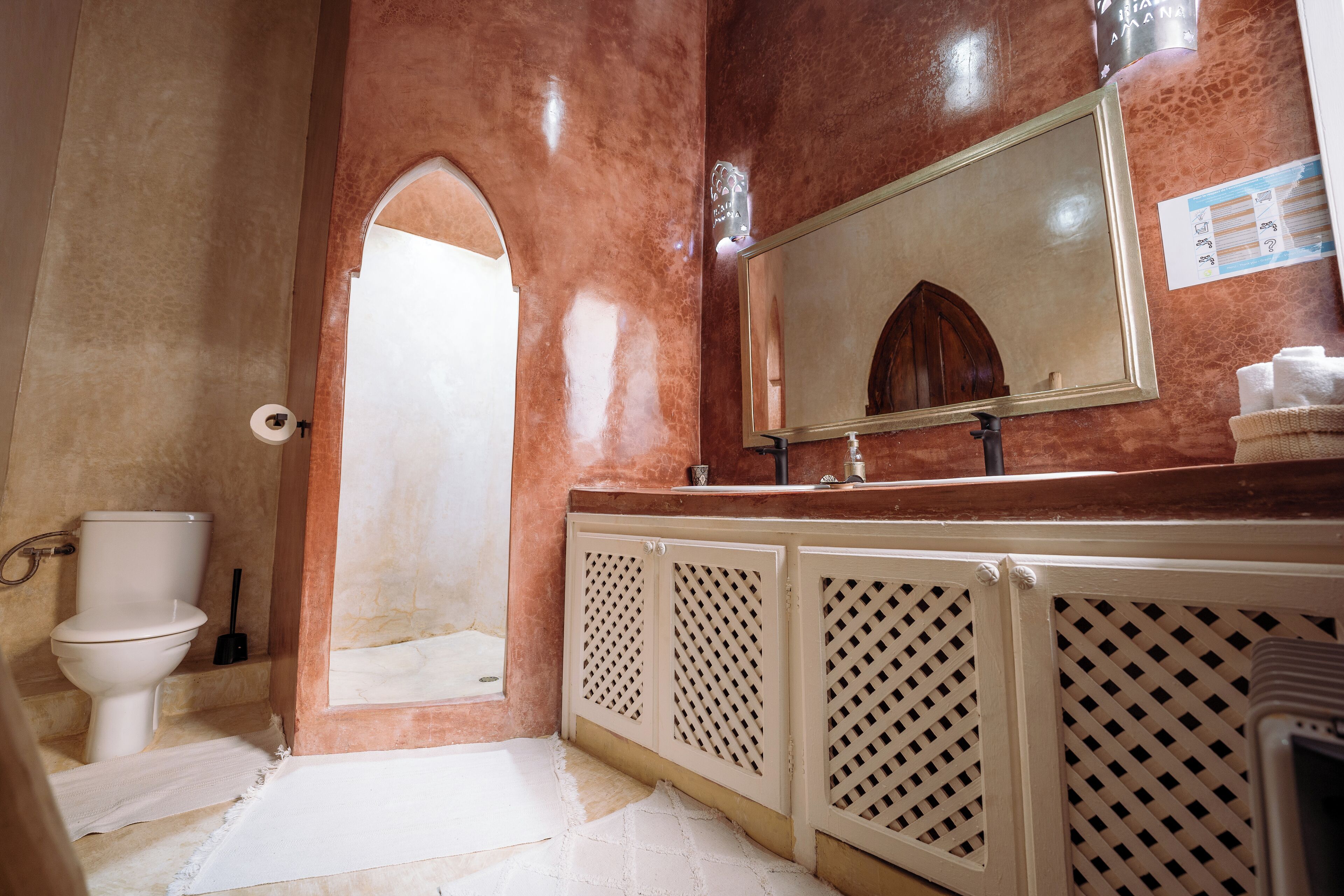 A bathroom with a toilet, sink, mirror, and shower area.