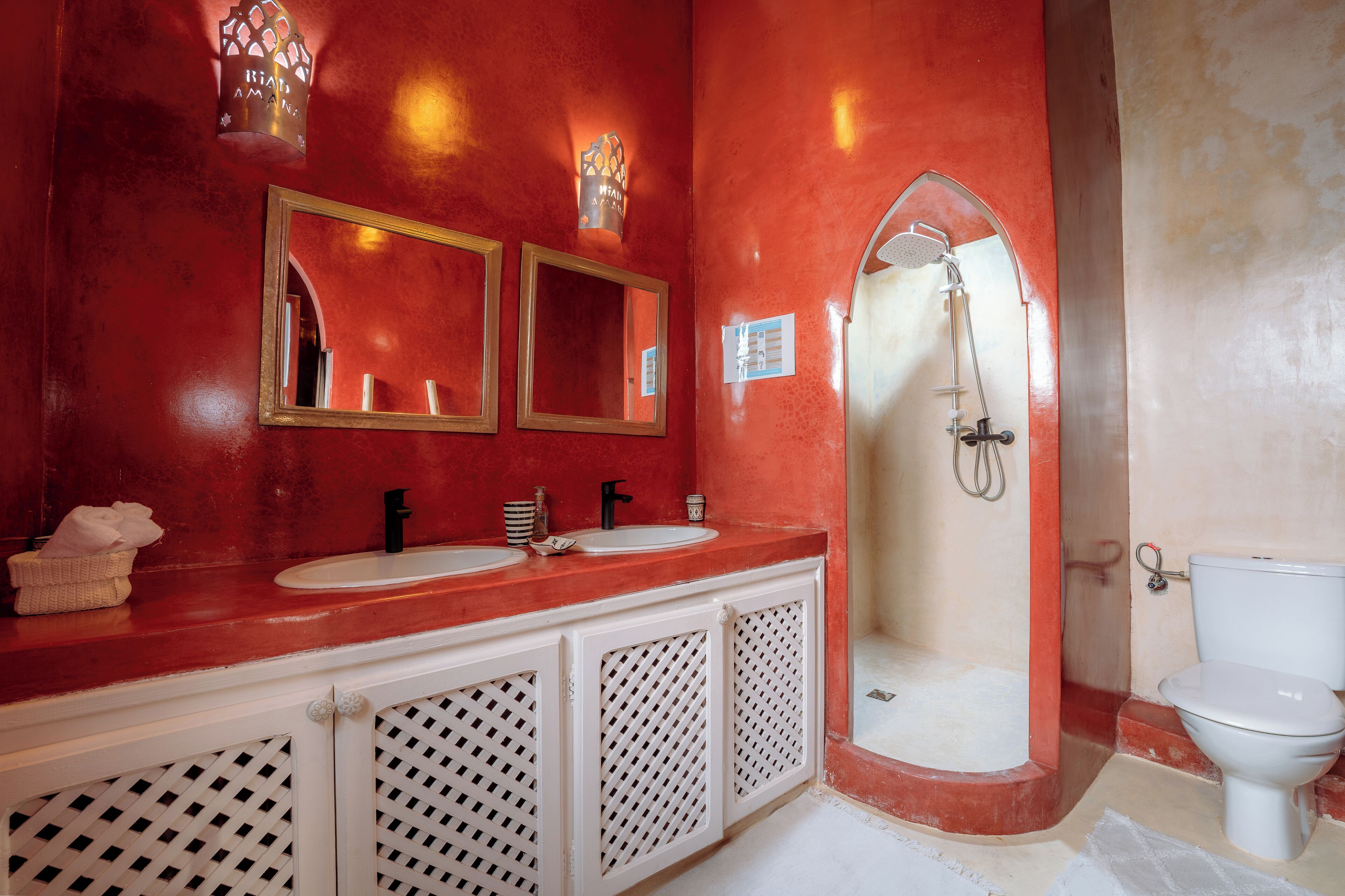 A bathroom with two sinks, a shower, and a toilet.