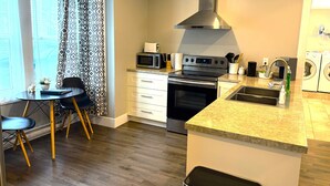 A modern kitchen with a built-in oven, microwave, stainless steel range hood, and a granite countertop. - Modern 1 Bedroom, 10 minute walk to Downtown (Moncton)