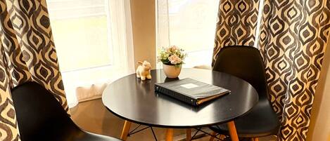 A round table with two black chairs, a small potted plant, and a notebook.