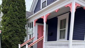 A house with a porch, a red door, and a staircase leading to the entrance. - Modern 1 Bedroom, 10 minute walk to Downtown (Moncton)