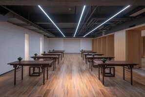 A conference room with multiple tables and chairs, wooden flooring, and modern lighting fixtures. - Vastroam Hotel (Yongtai)