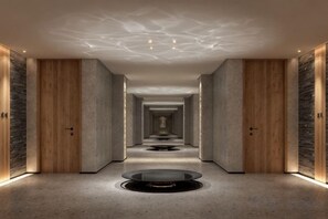 A hotel corridor with a central circular feature, wooden doors, and a patterned ceiling. - Vastroam Hotel (Yongtai)