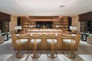 A modern bar area with a central island and bar stools, surrounded by bookshelves and a seating area. - Vastroam Hotel (Yongtai)