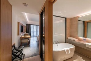 A modern bathroom with a freestanding bathtub, a large mirror, and a vanity with a sink. - Vastroam Hotel (Yongtai)