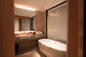 A modern bathroom with a freestanding bathtub, a vanity with a mirror, and a towel rack. - Vastroam Hotel (Yongtai)