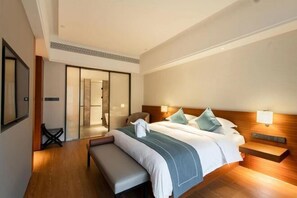 A modern hotel room with a large bed, a bench, a desk, and a sliding door leading to a bathroom. - Vastroam Hotel (Yongtai)