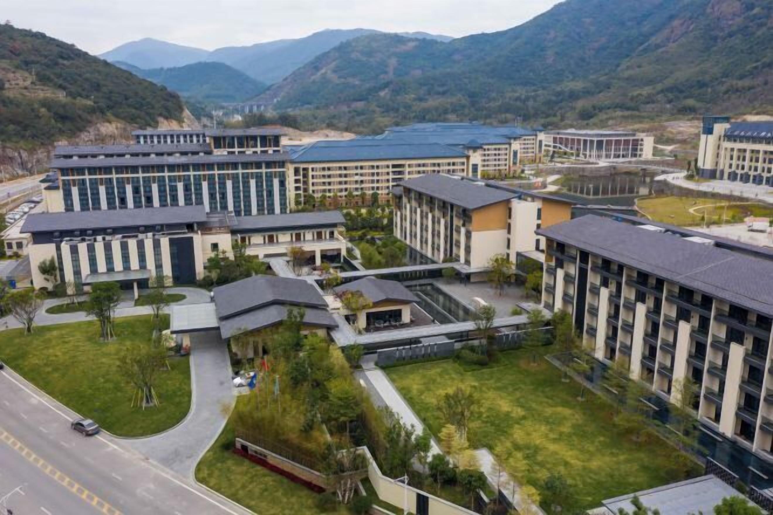 A modern hotel complex with multiple buildings, a central courtyard, and a road in the foreground.