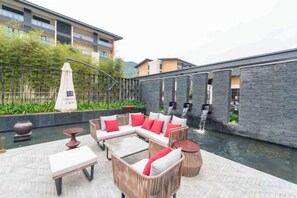 A rooftop terrace with outdoor seating, a water feature, and a view of a building. - Vastroam Hotel (Yongtai)