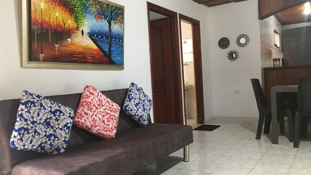 Uma sala de estar com sofá, quadro e área de refeições.