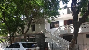 Um SUV branco estacionado na rua, uma árvore e um prédio com escadas.