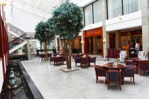 A spacious indoor area with multiple seating arrangements, a staircase, and a bar area. - Minqing Qiyuan Hotel (Minqing)