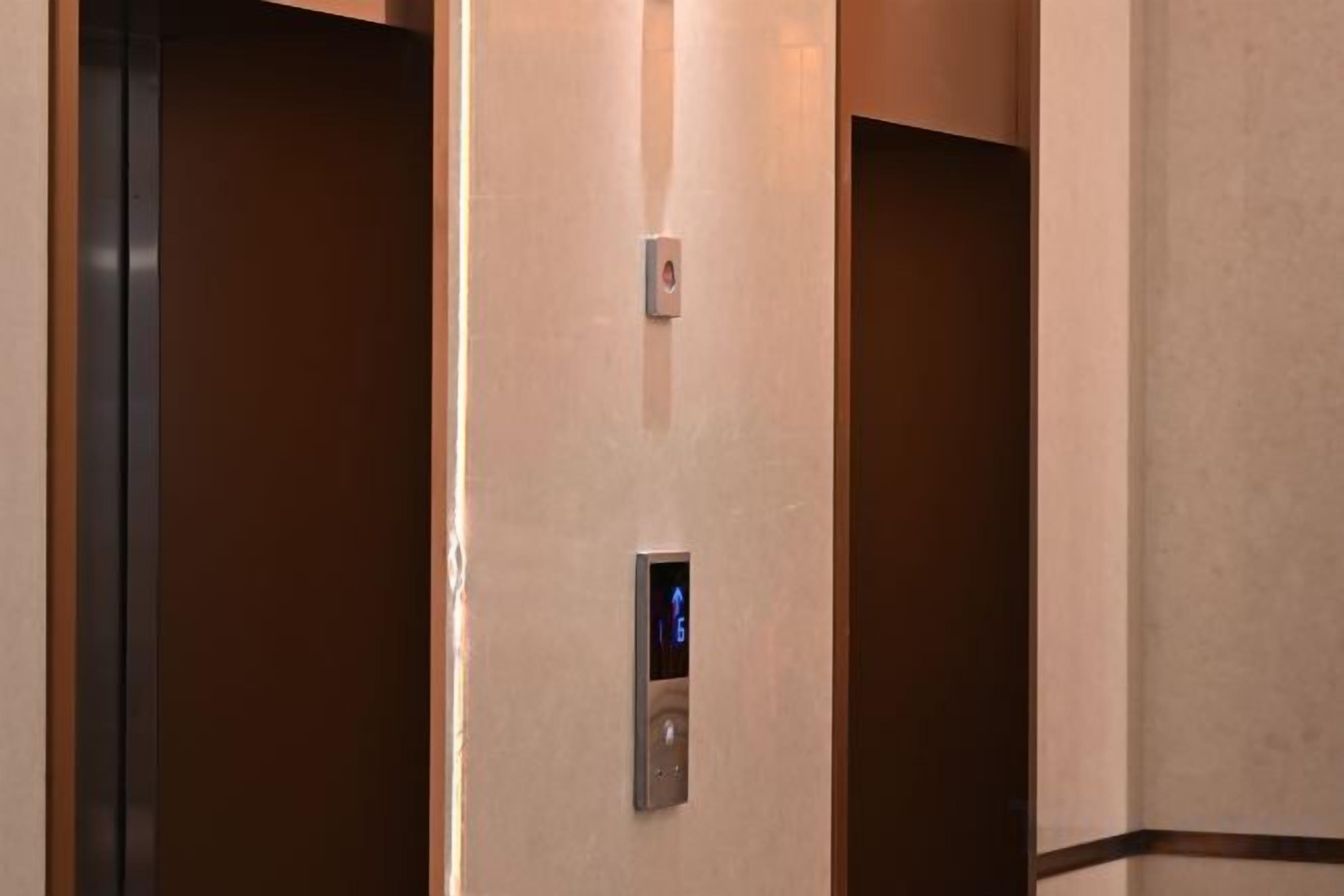 L’intérieur d’un ascenseur, avec un écran numérique et un panneau de boutons.