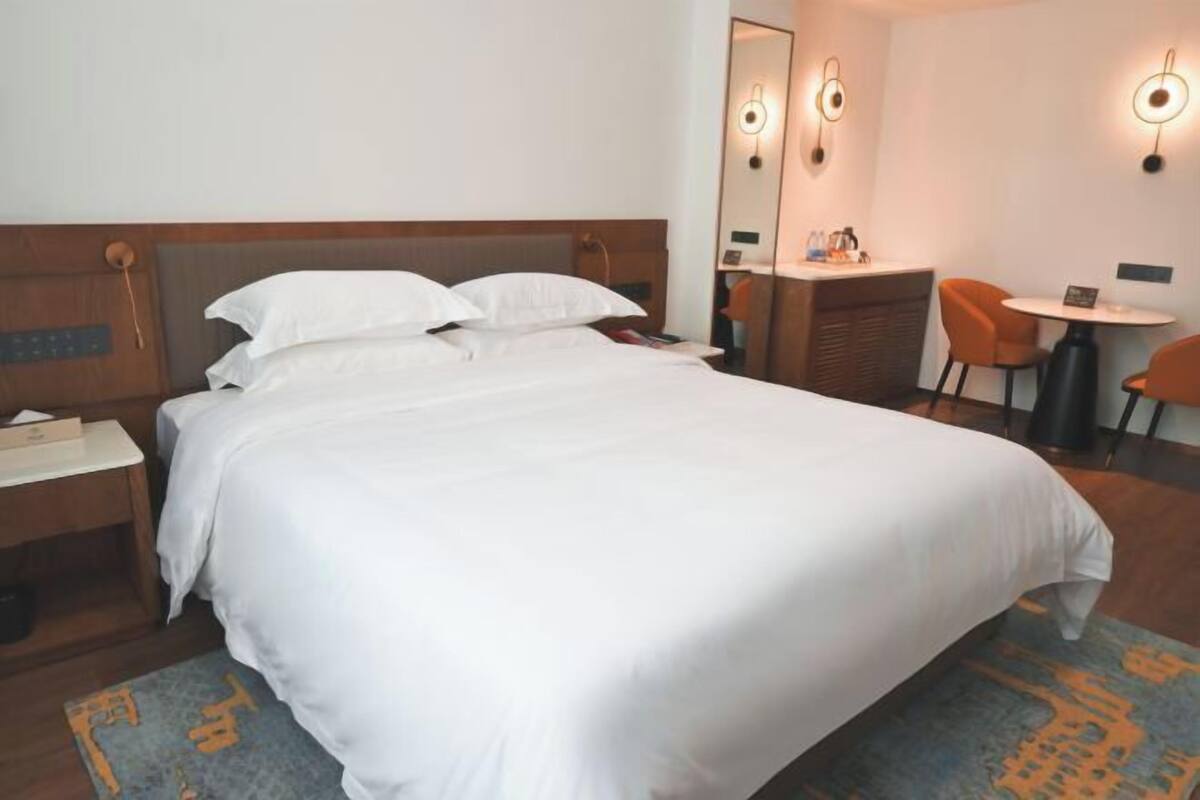 Une chambre d’hôtel avec un grand lit, une table de chevet et un bureau avec une chaise.