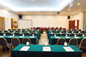 A conference room with rows of tables, chairs, and a stage with a podium. - Minqing Qiyuan Hotel (Minqing)