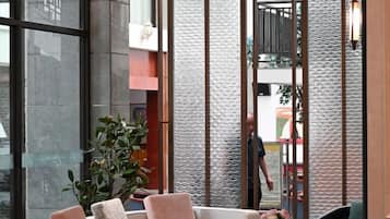 A modern interior with a sofa, a potted plant, and a textured wall.