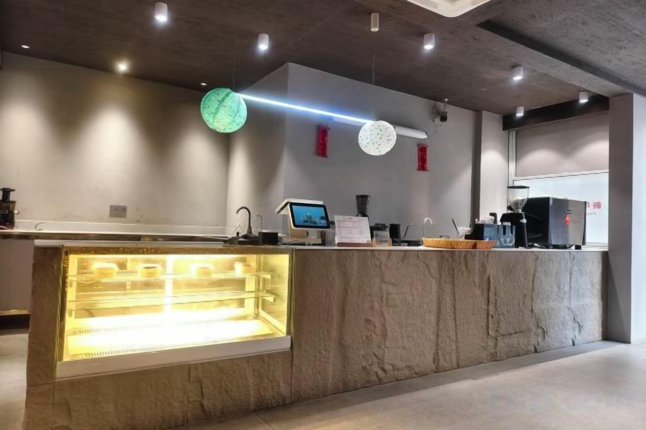 A modern counter with a glass display case, a digital screen, and a coffee machine.