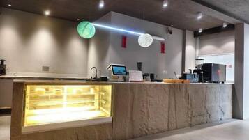 A modern counter with a glass display case, a digital screen, and a coffee machine.