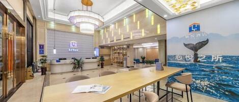 A modern hotel lobby with a reception desk, seating area, and a whale mural on the wall.