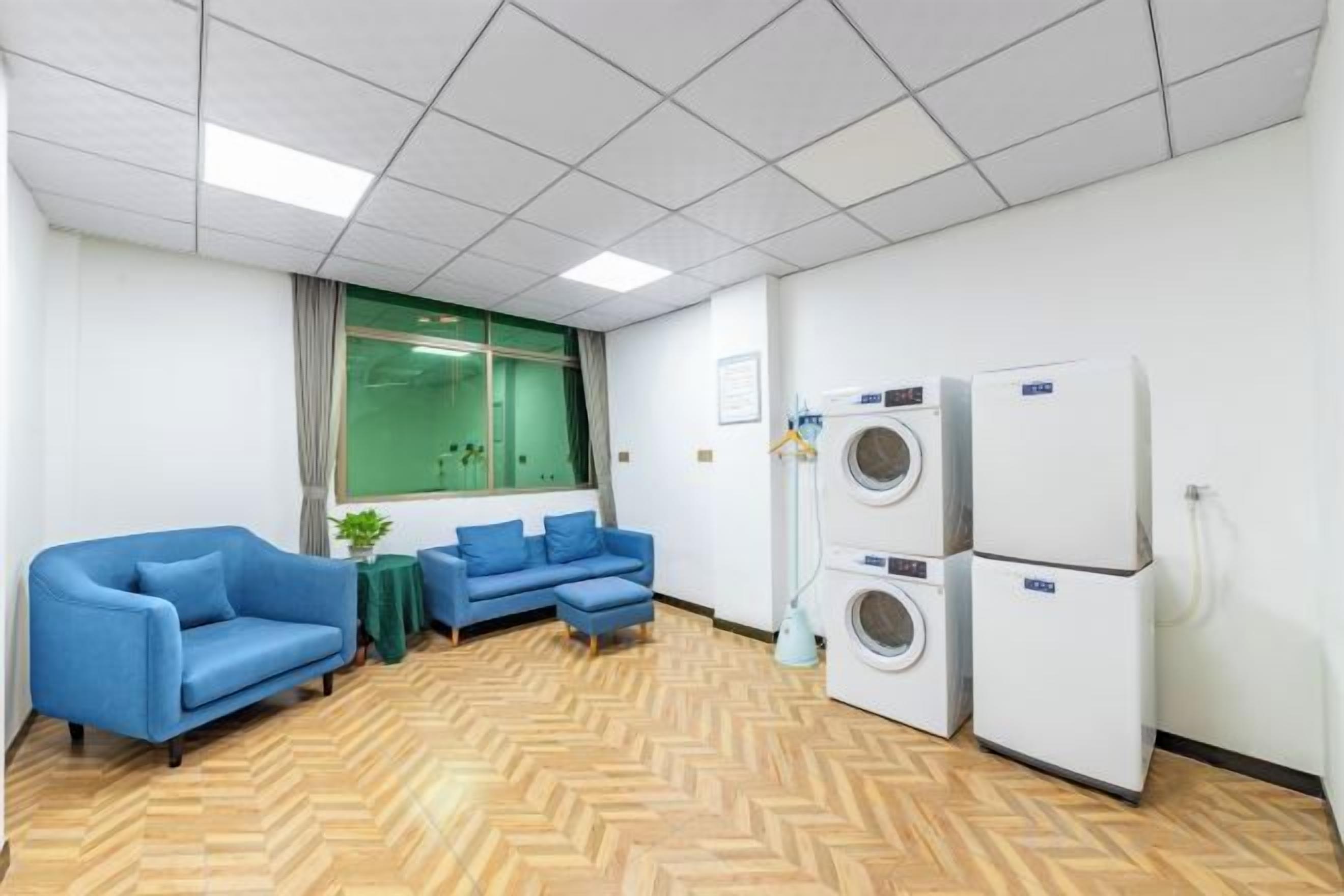 A room with a blue sofa set, a washing machine, and a green window.