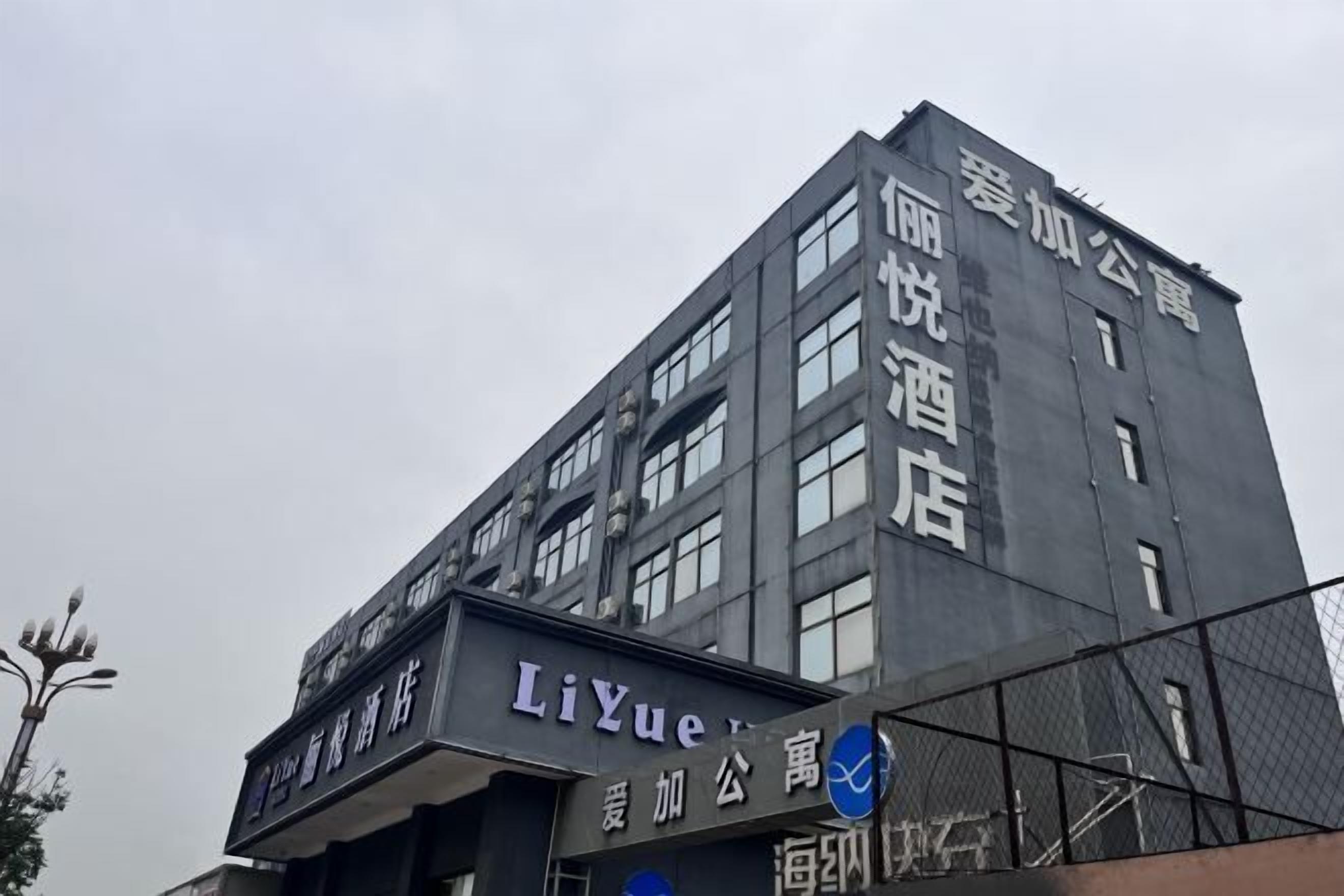 A multi-story building with signage for "LiYue" and "爱加公寓" (LiYue Public Housing).