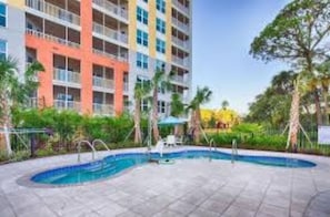 Relax by the pool surrounded by lush greenery and comfortable lounge chairs.