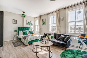 Relax in a stylishly designed room with a comfortable bed, sofa, and artwork-adorned walls.