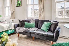 Relax in this stylish living room with a comfortable sofa, large windows, and a lush green plant.