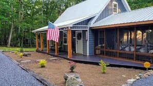 Ett tvåvåningshus med en inglasad veranda, en amerikansk flagga och en stensatt gångväg som leder till entrén.