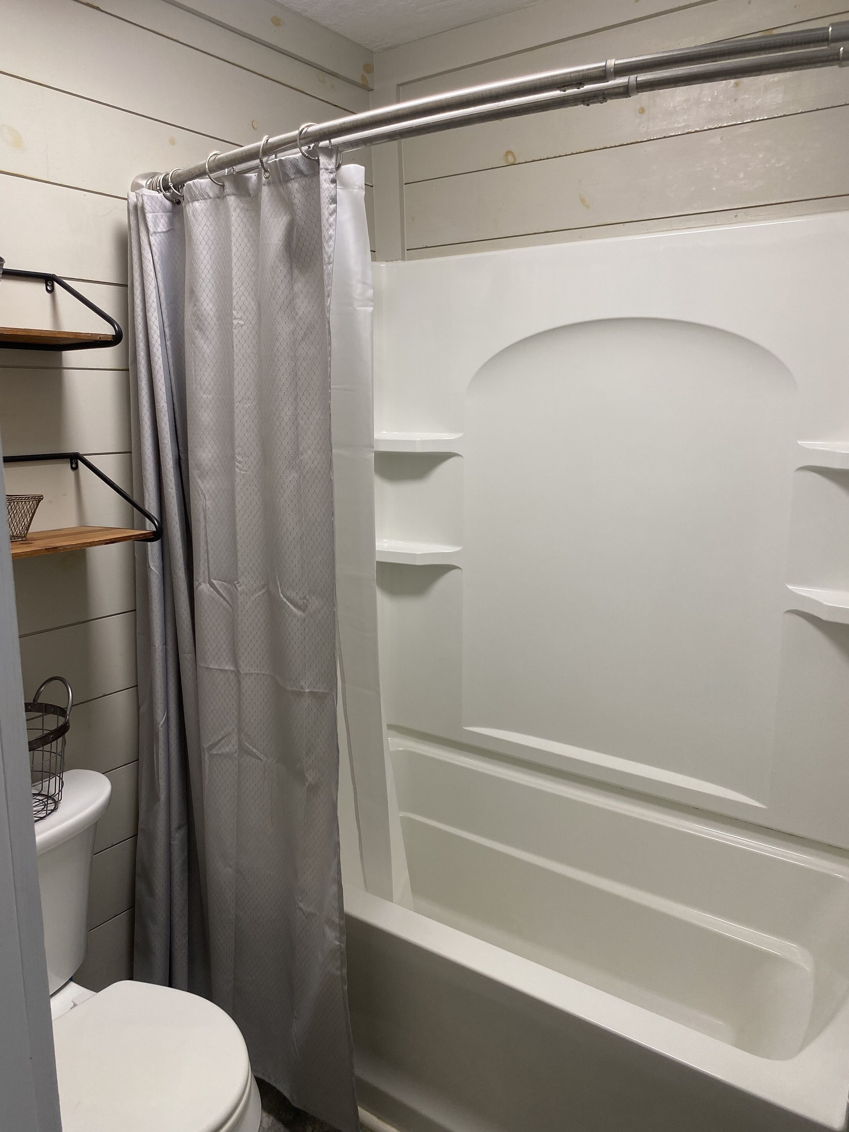 Une salle de bain avec une douche, des toilettes et des étagères.