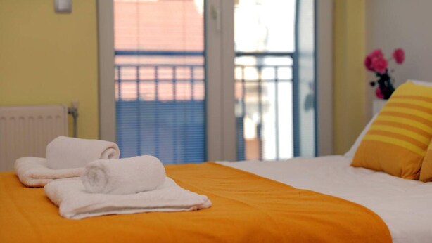 A hotel room with a bed, a window with blinds, and a view of the outside. - Unique Apartment Platnik (Skopje)