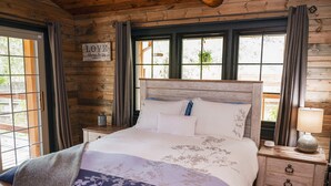 Ein Schlafzimmer einer Holzhütte mit einem Bett, Nachttischen und einem Schild an der Wand.
