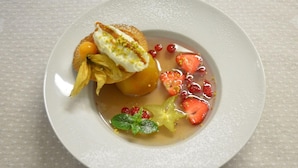 A dessert plate with a pastry, fruit, and a mint leaf. - Caesar Panoramic Hotel Restaurant (Bonnieux)