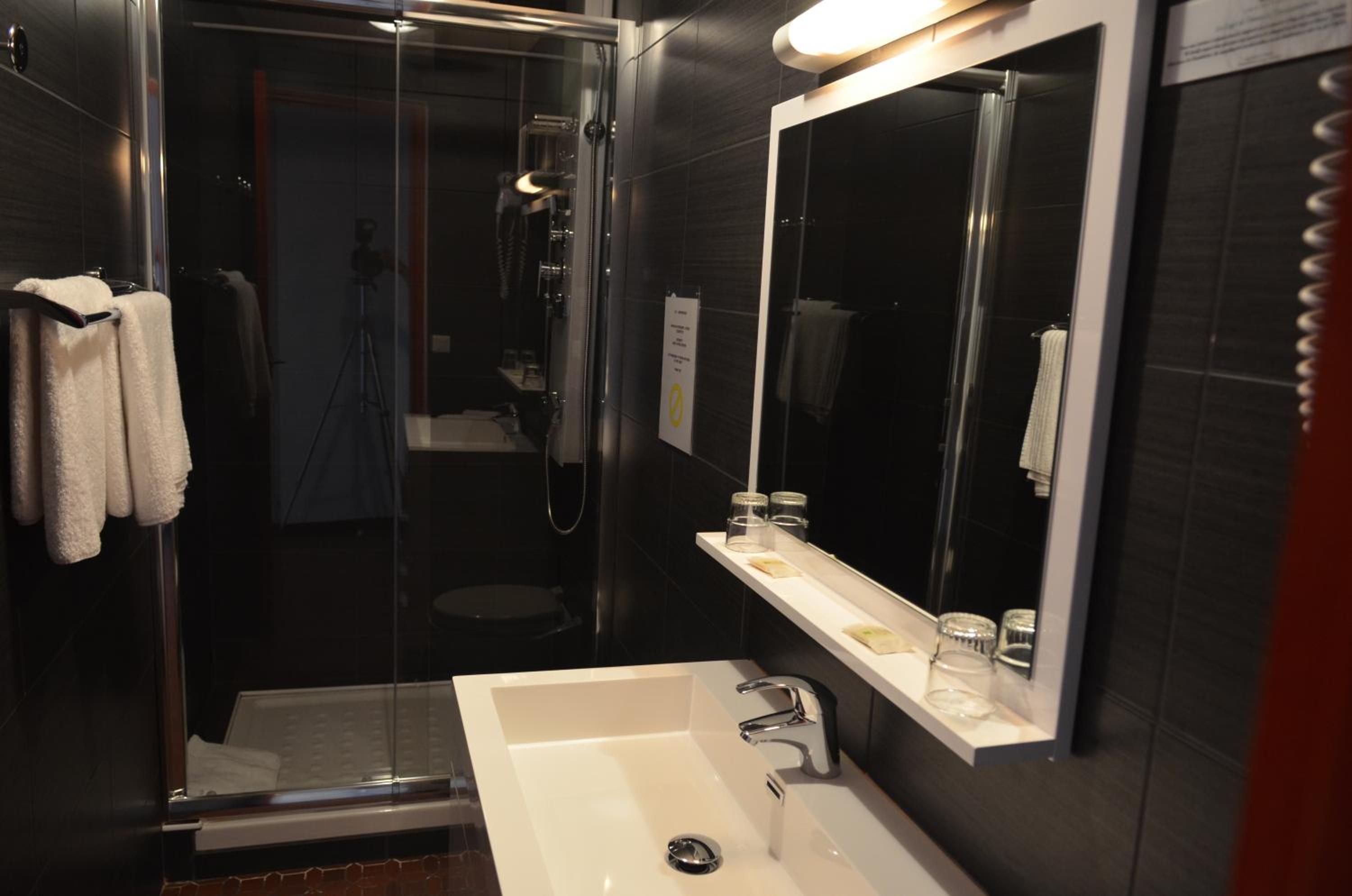 Une salle de bain moderne avec une douche à parois de verre, un lavabo blanc et un grand miroir.