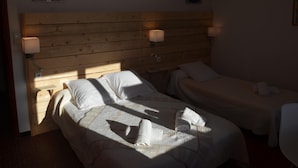 A hotel room with two beds, wooden headboard, bedside lamps, and a window allowing natural light. - Caesar Panoramic Hotel Restaurant (Bonnieux)
