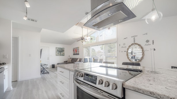 A modern kitchen with stainless steel appliances, a large island, and a view of the backyard.