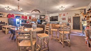 A rustic interior with wooden furniture, a kitchen area, and various decorations including a deer head and a mounted animal. - Pheasant Game Farm Missouri Vacation Rental! (Braymer)