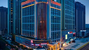 Ein modernes Hotel mit markanter Ecklage, großen Glasfenstern und einer gut beleuchteten Fassade.