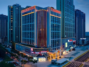 A modern hotel with a prominent corner location, large glass windows, and a well-lit facade. - Vienna International Hotel (Chengdu)