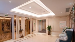 A hotel lobby with a polished marble floor, a reception desk, and a large decorative screen.