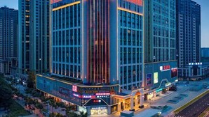 A multi-story hotel with a prominent corner entrance, large windows, and a visible sign for a restaurant.