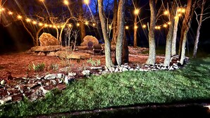 Een tuin met lichtjes, stenen en stoelen.