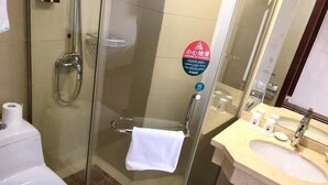 A glass-enclosed shower stall with a towel hanging on the door handle, a toilet, and a sink with toiletries. - Greentree Inn Suzhou Wuzhong District Fengjin Road Business Hotel (Suzhou)