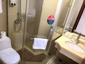 A glass-enclosed shower stall with a towel hanging on the door handle, a toilet, and a sink with toiletries. - Greentree Inn Suzhou Wuzhong District Fengjin Road Business Hotel (Suzhou)