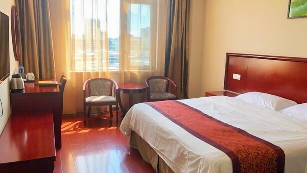 A hotel room with a large bed, a desk with a chair, a small table with two chairs, and a window with curtains. - Greentree Inn Suzhou Wuzhong District Fengjin Road Business Hotel (Suzhou)