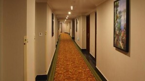 A hotel hallway with a carpeted floor, doors on both sides, and a ceiling light. - Greentree Inn Suzhou Fengjin Road Business Hotel (Suzhou)