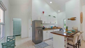 A modern kitchen with white cabinets, a stainless steel refrigerator, and a wooden island with chairs. - Modern Apartment in West End (West End)