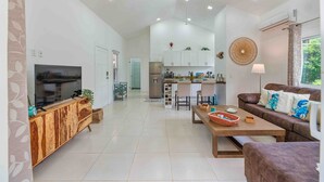 A spacious living area with a television, wooden cabinet, sofa, and a dining table. - Modern Apartment in West End (West End)
